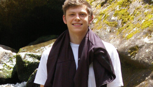 Young man standing in front of a waterfall